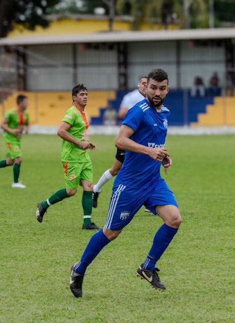 Vibrant soccer match featuring players in green and blue uniforms on a grassy field.