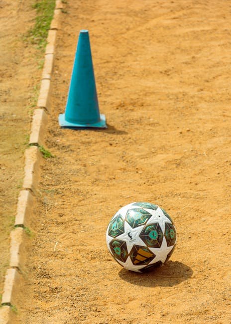 pexels-photo-36393264-36393264 A soccer ball next to a blue cone on a dusty playground in Ado Ekiti, Nigeria.