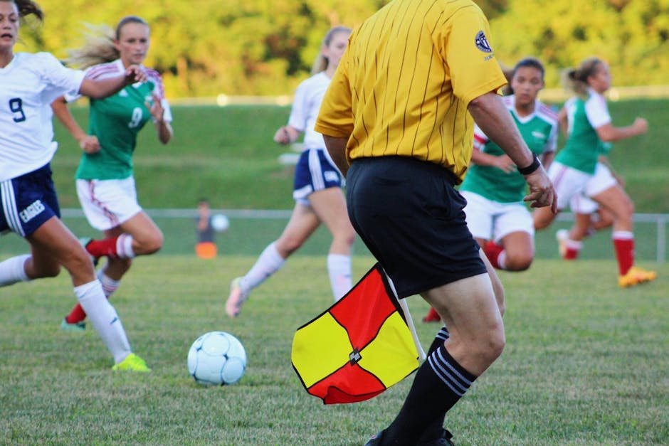 pexels-photo-906073-906073 Women's soccer match featuring players and referee on field in motion.